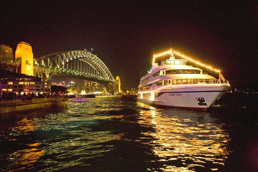 Sydney harbour dinner cruise boat on the water surrounded with lights and reflections