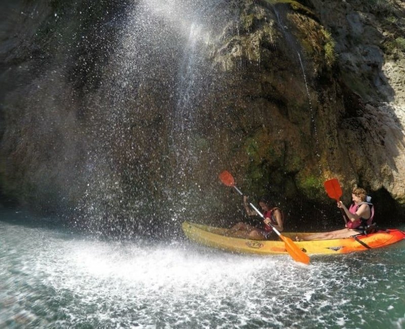 two people in a kayak under a waterfall in nerja malaga