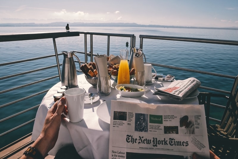 Person reading a newspaper having breakfast