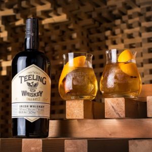 Image of Teeling Small Batch Whiskey and two drinks on wooden structure.