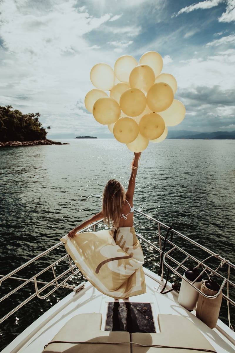 Woman holding balloons on edge of boat