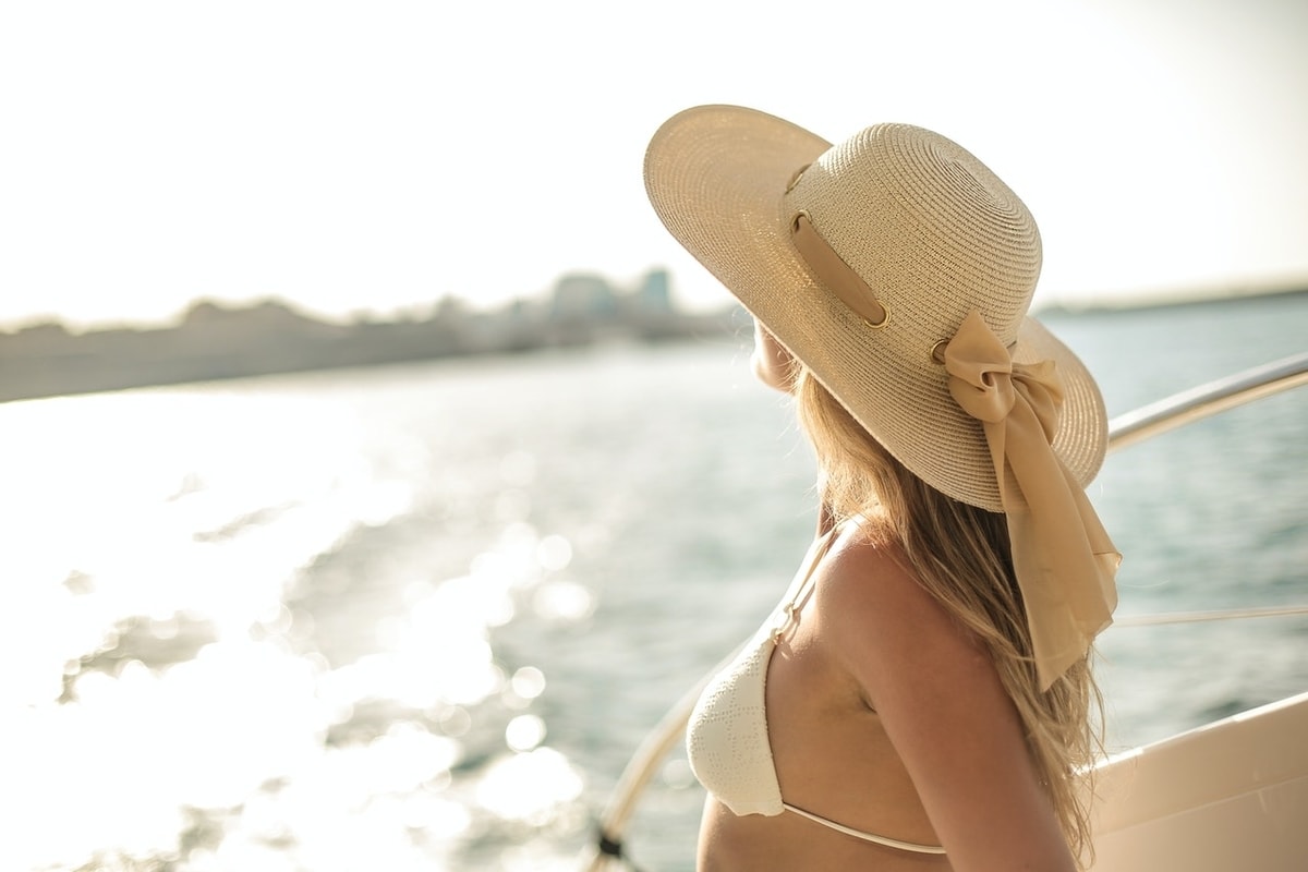 Lady on boat dock on river wearing sun hat.
