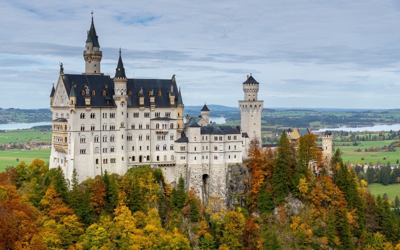 A far-away view of Neuschwanstein castle surrounded by trees