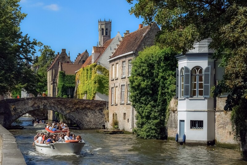 A canal in Brugge, Belgium with people in a gondola rowing passed a house