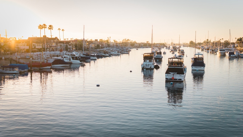 Boats sailing along the Newport Beach harbour at sunset