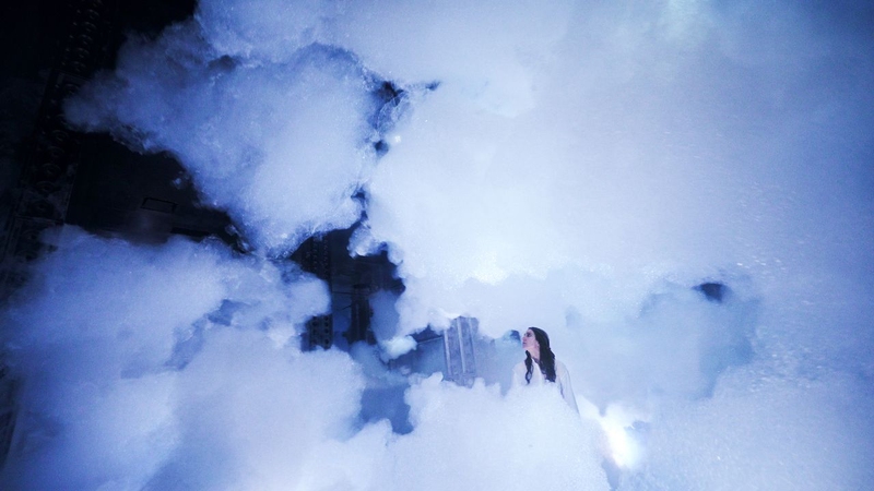 Person standing in a artificial cloud in the Massless Clouds Between Sculpture and Life exhibition at the Superblue Miami