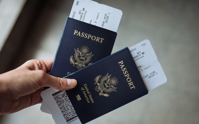 A person holding two American passports with boarding passes inside them