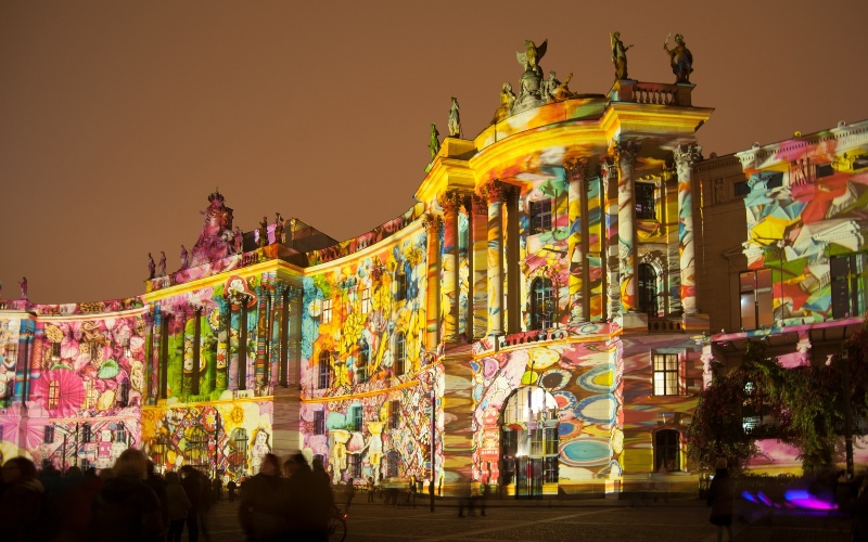 A building illuminated with various colorful patterns during the Berlin Festival of Lights