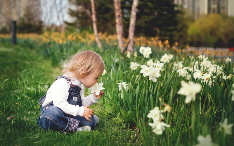 A young child peacefully smelling a flower in a garden
