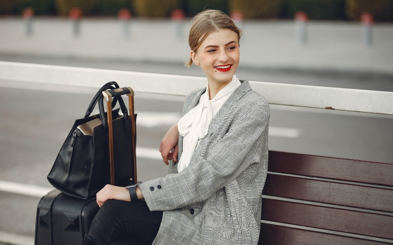 A smiling female traveler sitting next to her luggage