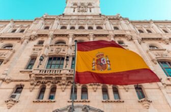 Photo of a Spanish flag blowing in the wind outside of a building in Madrid