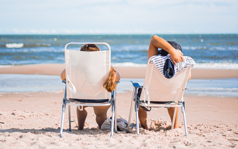 Two people relaxing in beach chairs in front of the sea