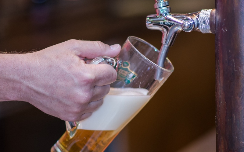 Closeup of a person pouring a glass of draught beer