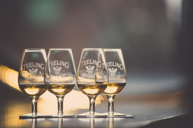 Image of four Teeling Whiskey sampling glasses with whiskey on a bar table.