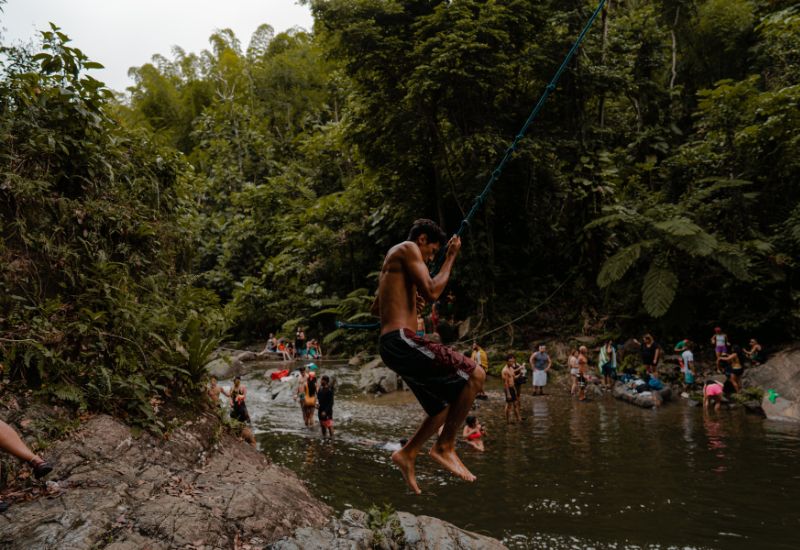 Man swinging on a rope into waterfall
