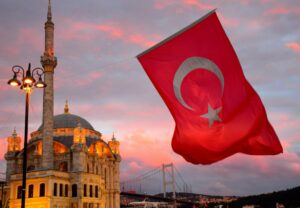 Red Turkish flag flying next to a mosque
