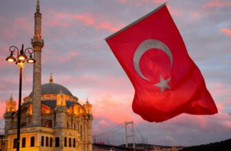 Red Turkish flag flying next to a mosque