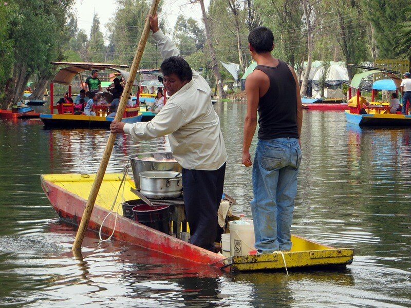 Two vendors rowing a boat on the river selling food to tourists